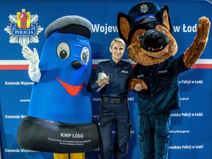 Policjanta stoi pomiędzy dwoma dużymi maskotkami.