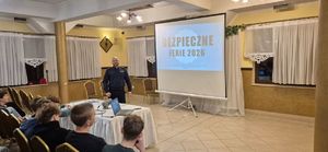 Umundurowany policjant stoi przed grupą młodzieży.