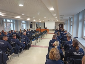 Słuchacze szkolenia siedzą w ławkach na sali.