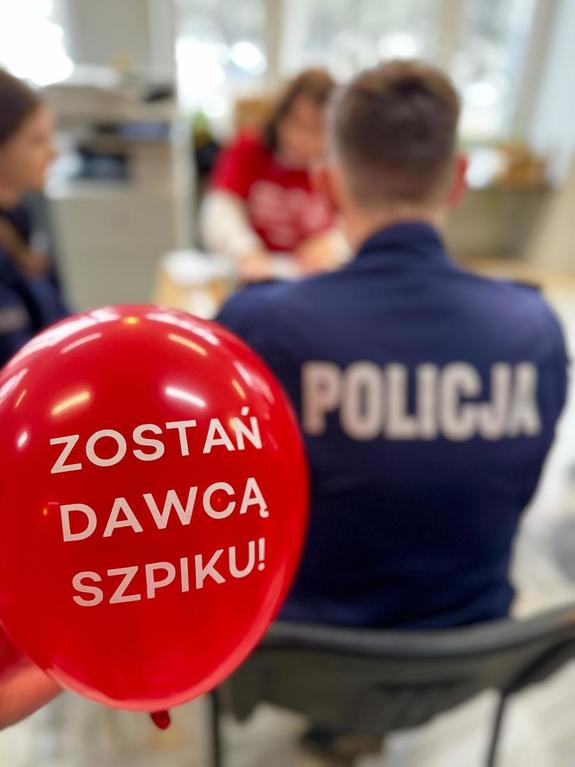 Balona czerwony zostań dawcą szpiku, policjant siedzi tyłem.