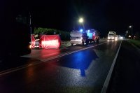 Miejsce wypadku na drodze krajowej numer 95, policjanci wykonują oględziny, widoczny parawan, radiowóz policyjny i wóz strażacki stojące na sygnałach