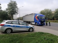 teren miasta , na zdjęciu widać oznakowany radiowóz Wydziału Ruchu Drogowego i policjantów kontrolujących samochód ciężarowy