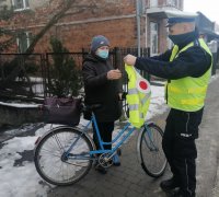 policjant ruchu drogowego przekazujący kamizelkę odblaskową rowerzystce