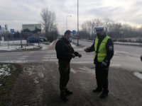 policjant ruchu drogowego przekazujący odblaskową opaskę mieszkańcowi