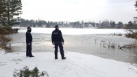 Dwóch policjantów stoi na brzegu zamarzniętego zbiornika wodnego