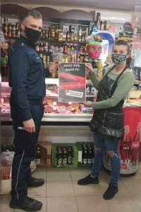policjant na terenie sklepu przekazuje pracownicy plakat