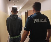 policjant wraz z zatrzymanym prowadzonym przez korytarz policyjnego aresztu