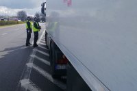 na zdjęciu widać dwóch policjantów stojących przy kabinie kontrolowanego pojazdu ciężarowego