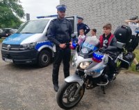 policjant piotrkowskiej drogówki stoi przy motocyklu policyjnym, na motocyklu siedzi dziecko biorące udział w pikniku z okazji Dnia Dziecka