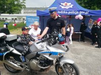 dziecko siedzi na policyjnym motocyklu podczas pikniku z okazji Dnia Dziecka