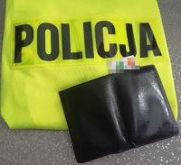 na zdjęciu kamizelka z napisem policja a na niej portfel z wystającą kartą bankomatową