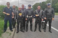 policjanci wraz z motocyklistami trzymając w ręku naklejki