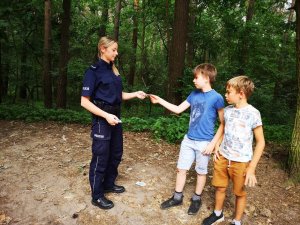policjantka rozmawia z chłopcami o bezpieczeństwie oraz wręcza elementy odblaskowe