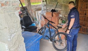 policjant w pomieszczeniach piwnicy zabezpiecza odnaleziony  rower pochodzący z przestępstwa kradzieży