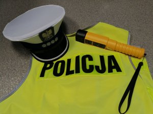 kamizelka policyjna, z czapką policjanta ruchu drogowego oraz urządzeniem do badania stanu trzeźwości,