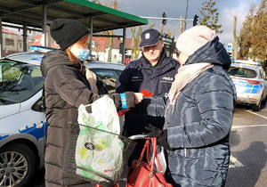 Policjant i młodzież z Młodzieżowej Grupy Pożarniczej podczas rozdawania odblasków