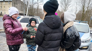 Policjant i młodzież z Młodzieżowej Grupy Pożarniczej podczas rozdawania odblasków