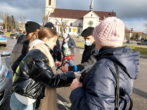 Policjant i młodzież z Młodzieżowej Grupy Pożarniczej podczas rozdawania odblasków