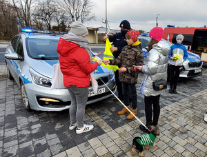 Policjant i młodzież z Młodzieżowej Grupy Pożarniczej podczas rozdawania odblasków