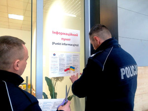 policjanci zawieszający ulotki informacyjne w języku polskim i ukraińskim