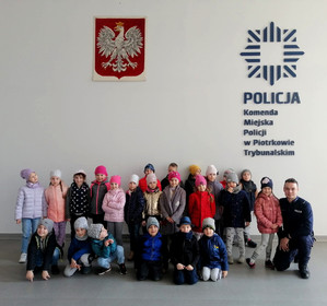 policjant na zdjęciu z grupą przedszkolaków w auli piotrkowskiej jednostki Policji