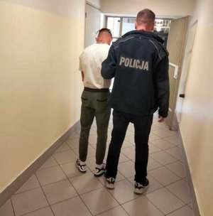 zatrzymany z policjantem, stoją tyłem w korytarzu