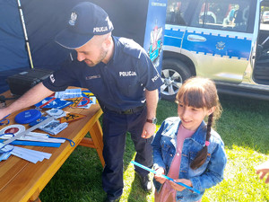 policjant przekazujący elementy odblaskowe dziewczynce