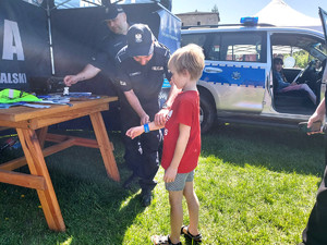 policjant zakłada chłopcu opaskę odblaskową na rękę