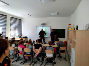 policjant ze strażnikiem leśnym podczas spotkania w sali szkolnej z uczniami