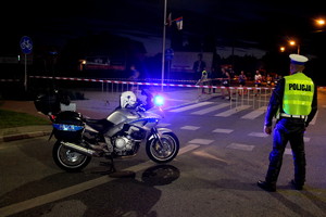 policjant zabezpieczający trasę biegu półmaratonu, obok motocykl policyjny