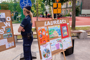 policjantka przygląda się pracom plastycznym biorącym udział w konkursie ,,bezpieczeństwo Moje i Twoje&quot;