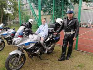 policyjna motocyklista pozuje do zdjęcia, na motocyklu uczennica szkoły podstawowej podczas pikniku z Policją