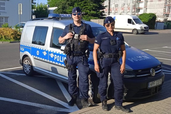 policjanci stojący przy radiowozie oznakowanym