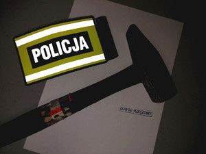 młotek, którym 46-latek uszkodził pojazd, obok opaska z napisem policja