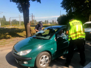 policjant przekazuje ulotki informacyjne kierowcom dotyczące prawidłowych zachowań  w rejonach i na przejazdach kolejowych