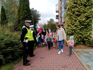 policjanci z dziećmi przed budynkiem przedszkola