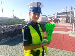 Policjantka trzymająca elementy odblaskowe.