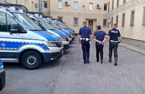 Policjanci prowadzący zatrzymanego do policyjnego aresztu.