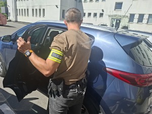 Policjant przy radiowozie, w środku zatrzymany.