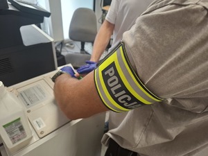 Policjant podczas pobierania śladów linii papilarnych od podejrzanego.