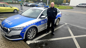 Policjant na tle radiowozu.