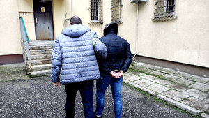 Policjant prowadzący zatrzymanego do pomieszczenia dla osób zatrzymanych.