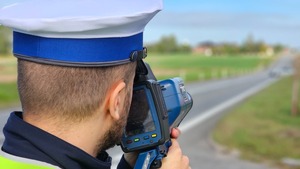 Policjant w białej czapce mierzący prędkość.