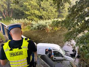 Policjant na miejscu zdarzenia podczas wyciągania pojazdu ze zbiornika wodnego.