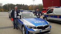 Maciej Wisławski wraz z policjantem WRD KMP w Łodzi stoją przy oznakowanym radiowozie