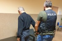 korytarz komendy, policjant zakuwa w kajdanki zatrzymanego mężczyznę