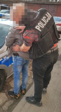 Policjant przeszukuje zatrzymanego.