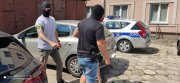 Policjanci prowadzą zatrzymanego przez dziedziniec Komisariatu.