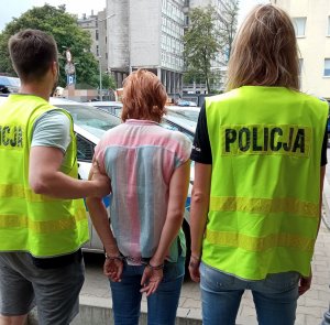 Policjanci konwojują zatrzymaną kobietę.