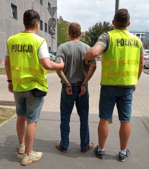 Policjanci konwojują sprawce zabójstwa.